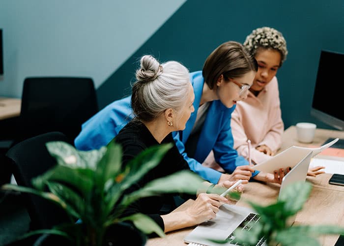 Three colleagues reviewing work together on a laptop