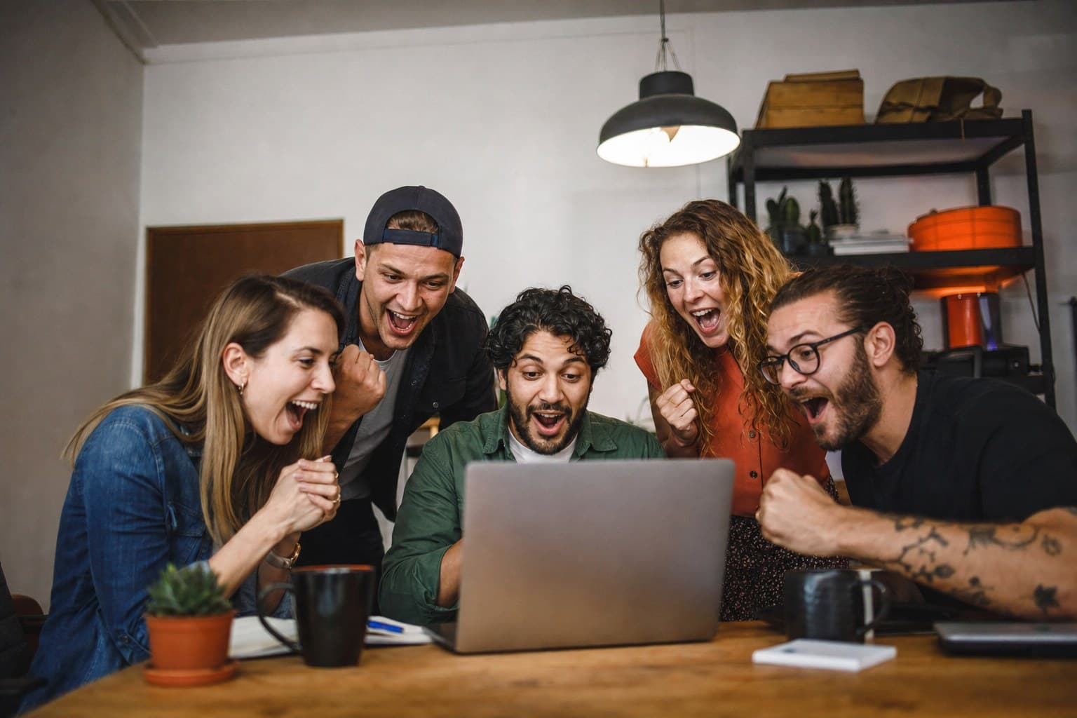 A team reacting to a result together around a laptop